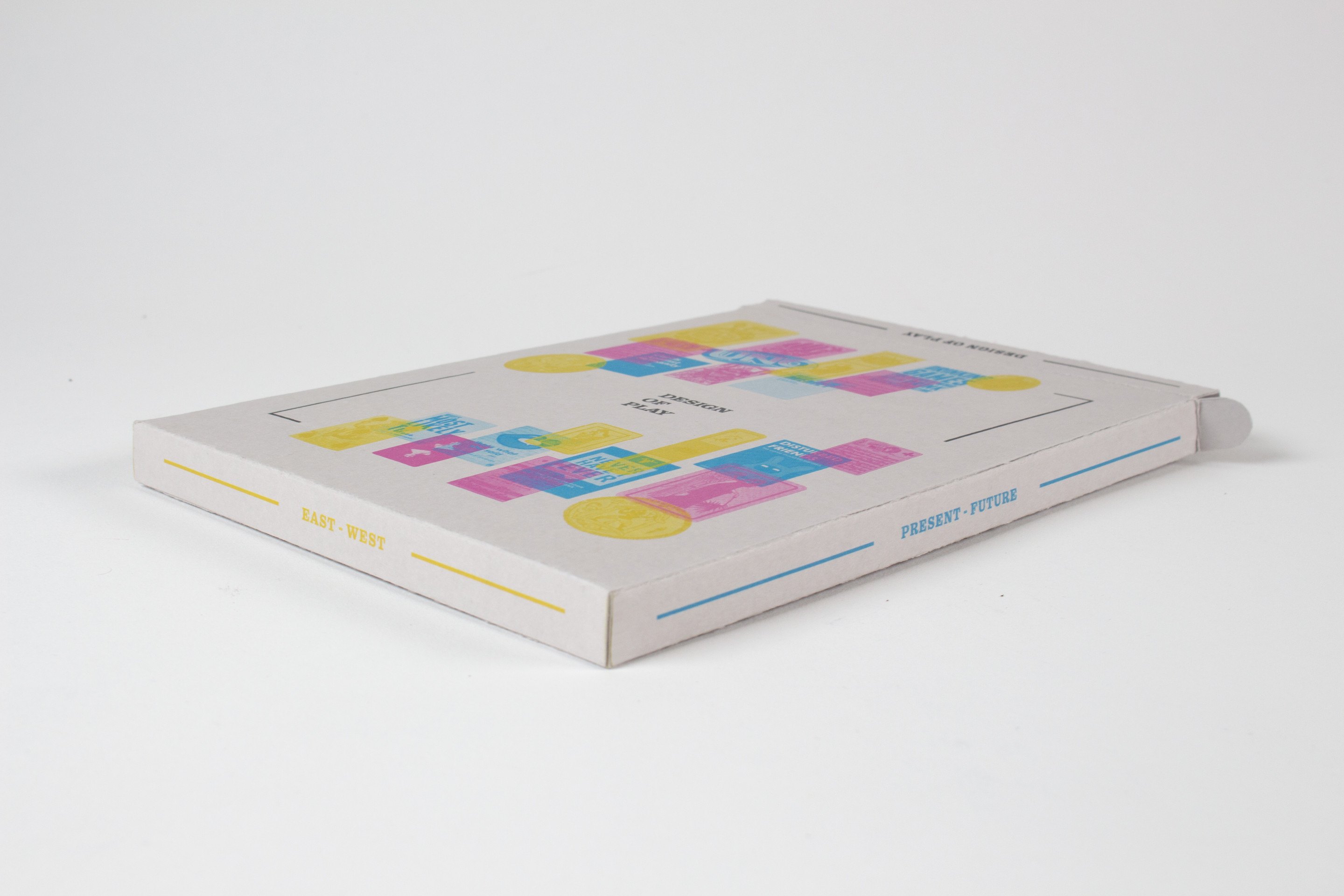 The slipcase from the other side at a low angle, the card-grid cover catching the light