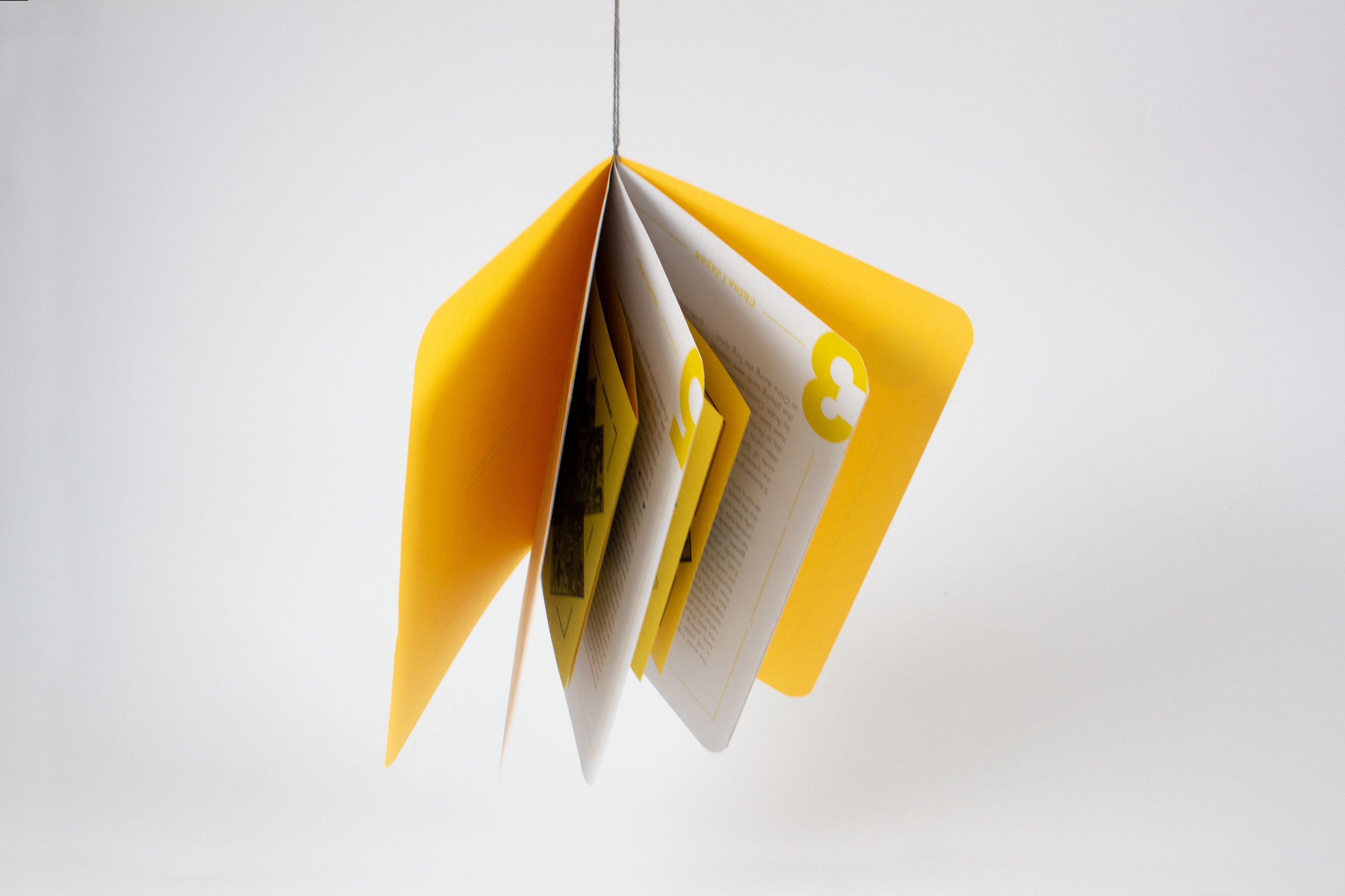The yellow book stood open on its end so its pages fan out, the grey binding thread hanging below