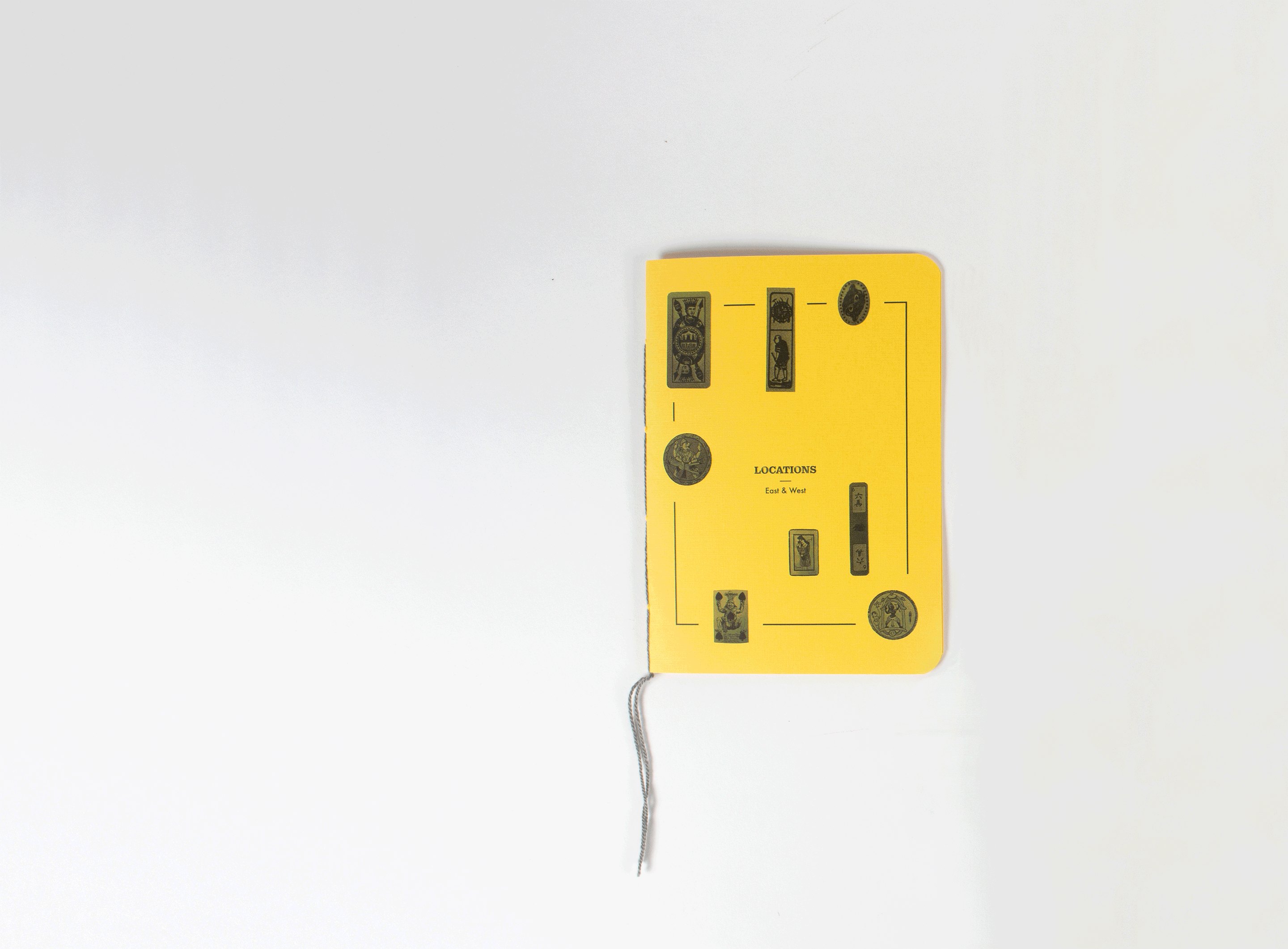 The yellow book closed and photographed from above, its thread trailing across the white surface
