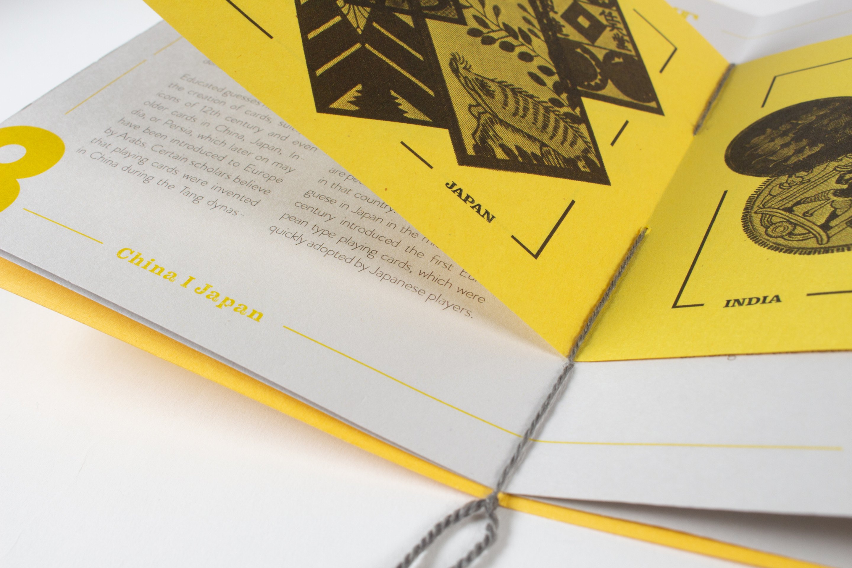 The first book open at a spread on Japan and India, black woodcut-style card illustrations across both pages