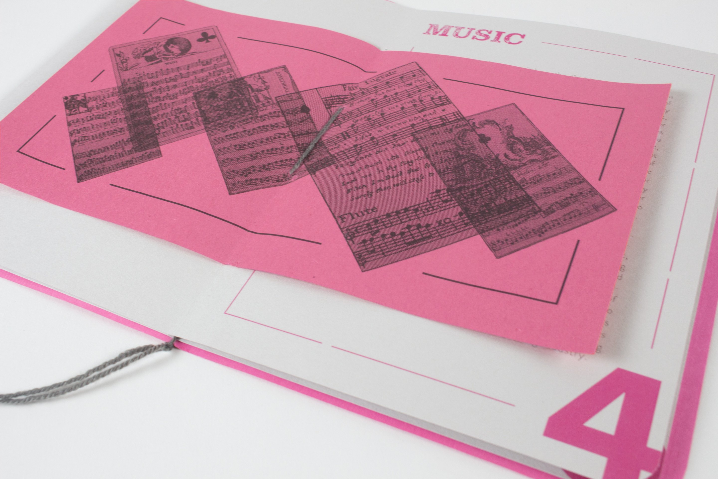 The second book open on a spread about Music decks, small printed cards arranged in a diagonal cascade on a magenta ground