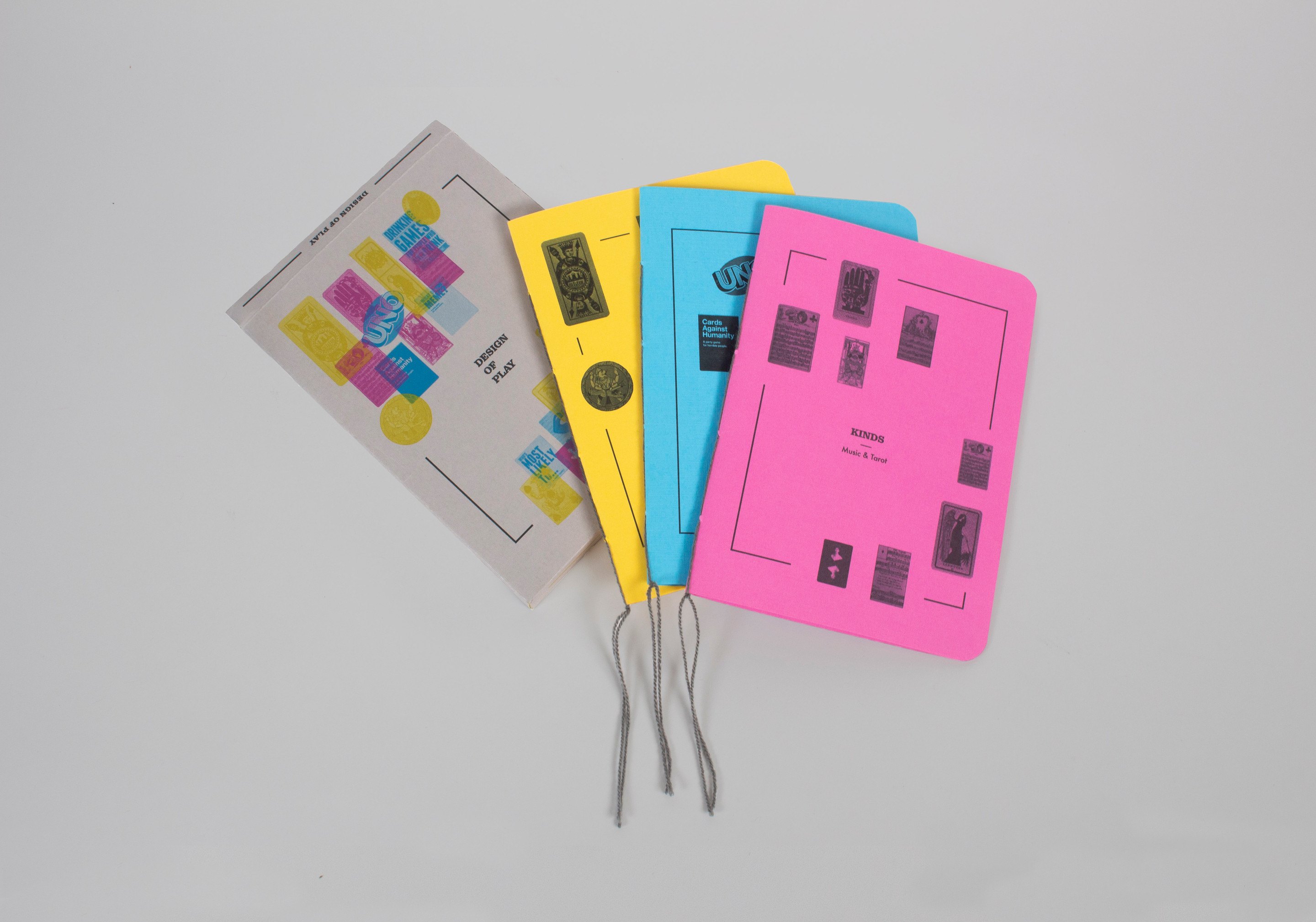The whole set fanned out: the slipcase behind and the yellow, blue and magenta books stepped in front of it, all four threads hanging