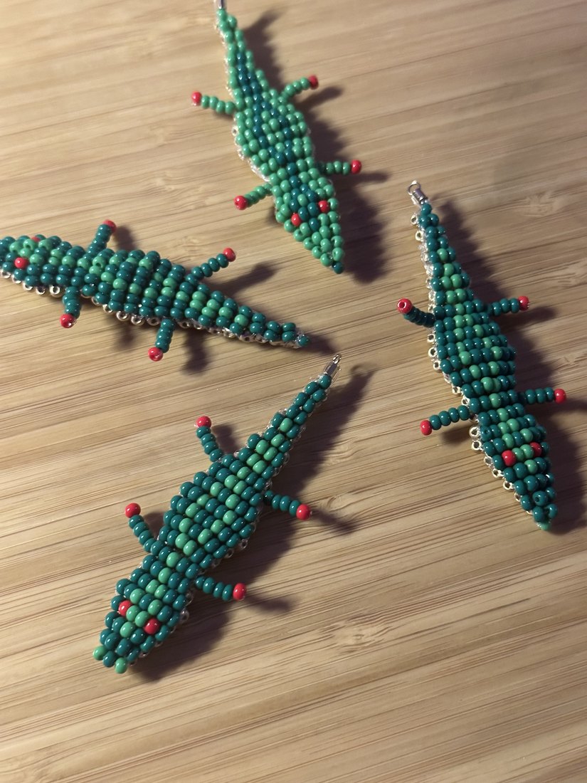 Four beaded crocodiles on a wooden board