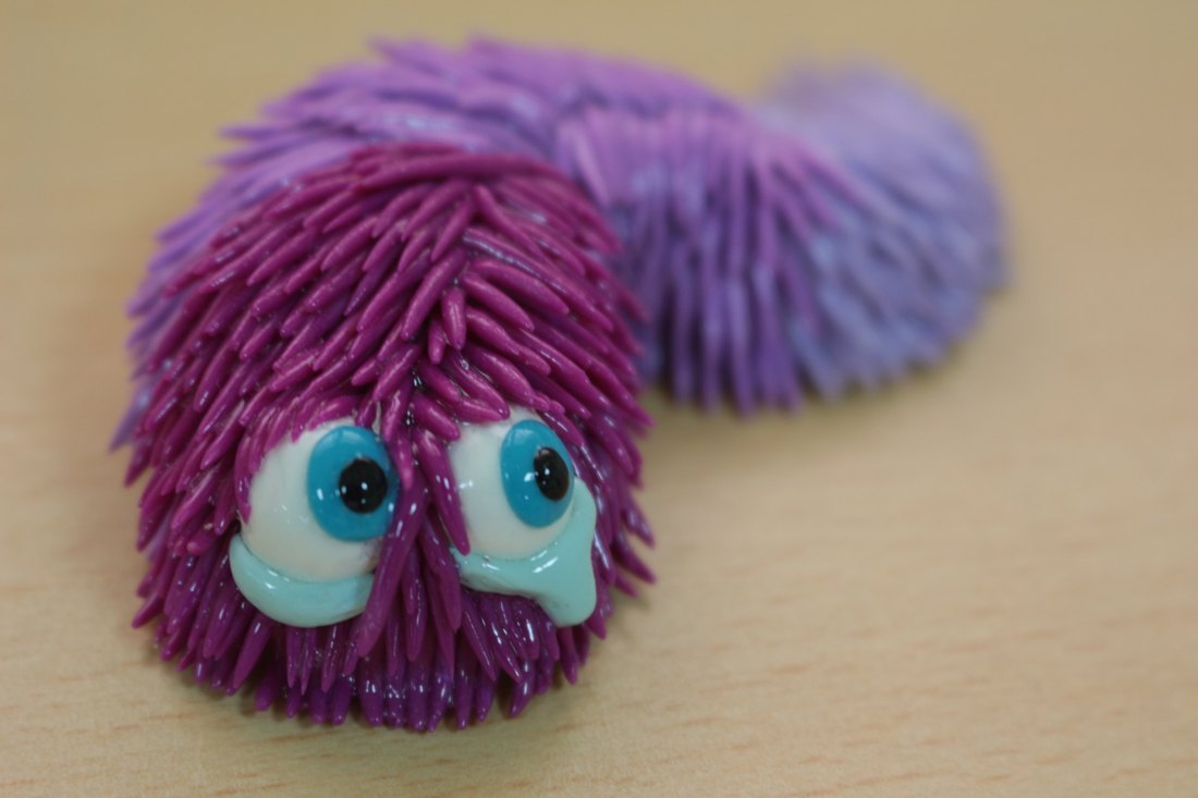 A purple furred caterpillar with wide eyes