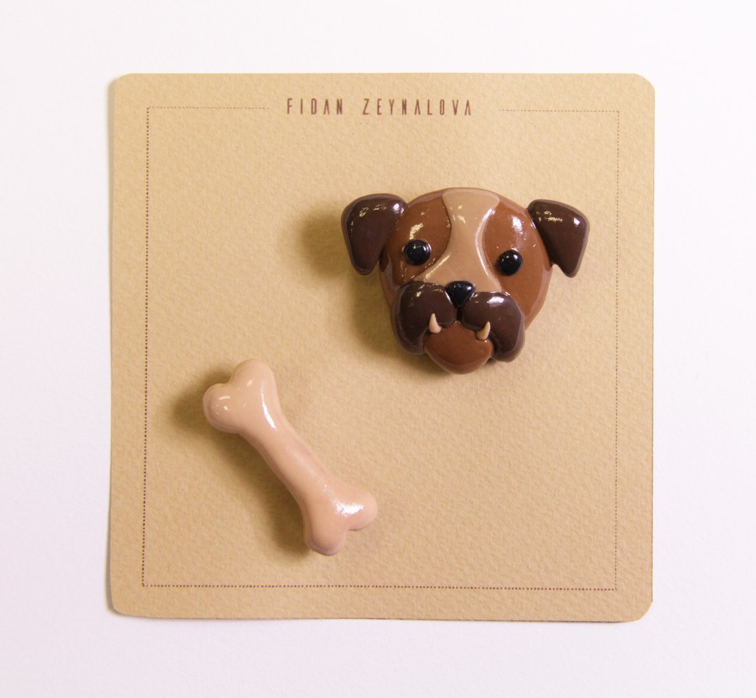 A brown dog face pin with a bone, on a kraft card