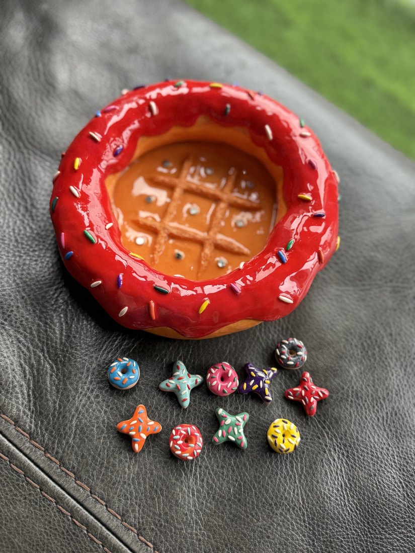 A sprinkled doughnut dish beside tiny clay charms