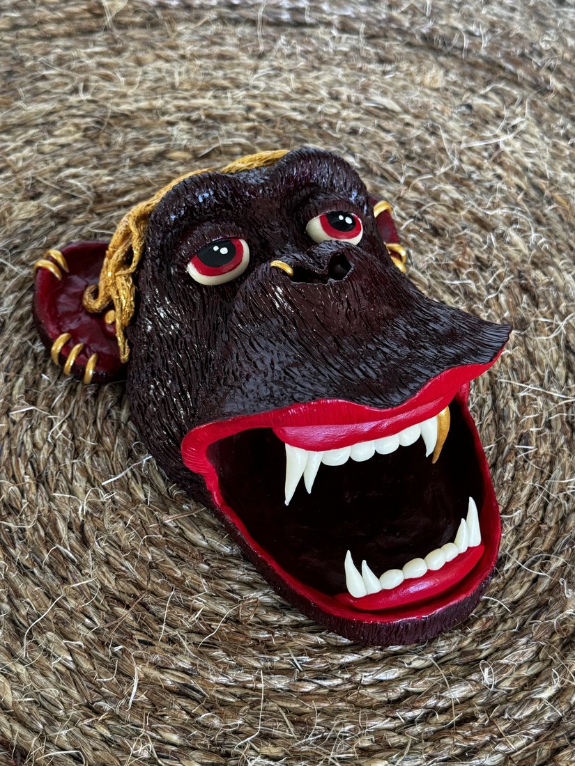 A clay gorilla face mounted on a woven mat