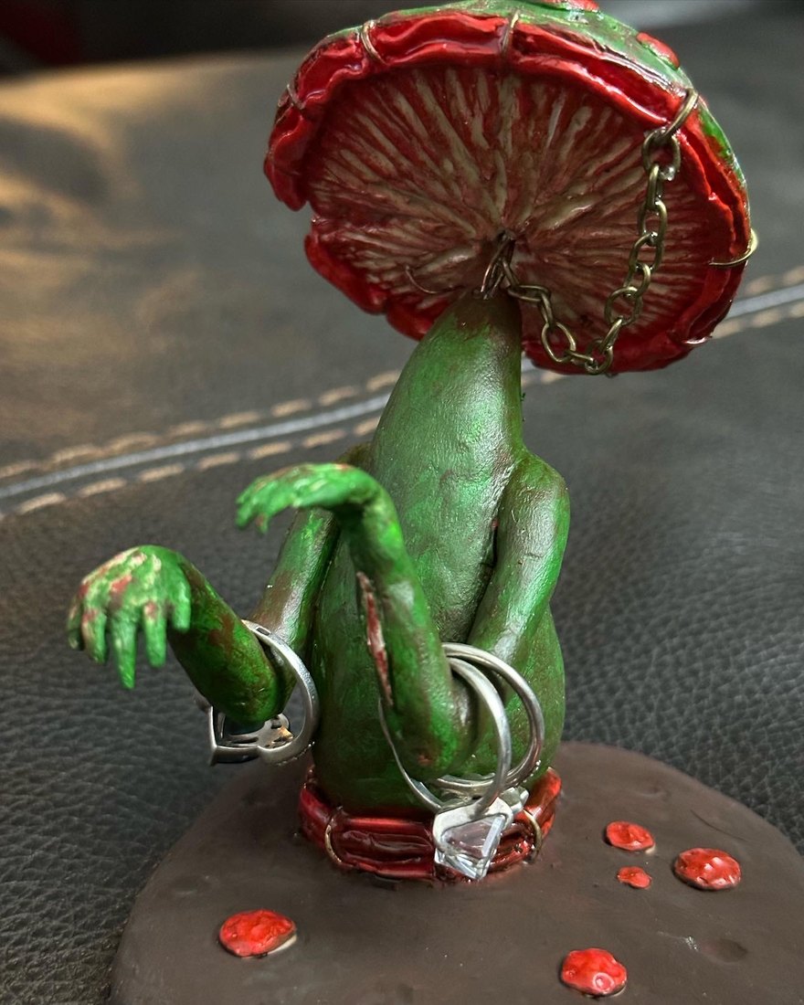 A green mushroom creature with a red cap