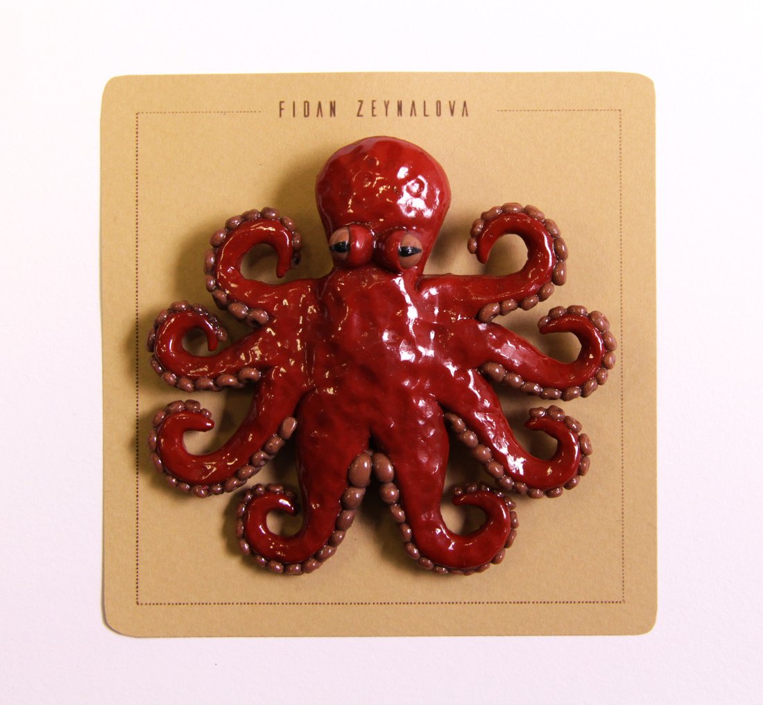 A red octopus pin on a kraft card