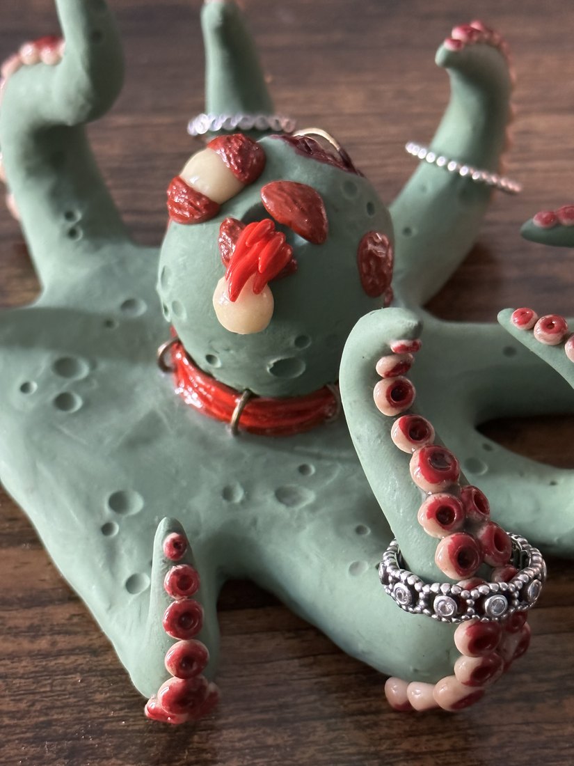 A pale green octopus figure with a beaded chain