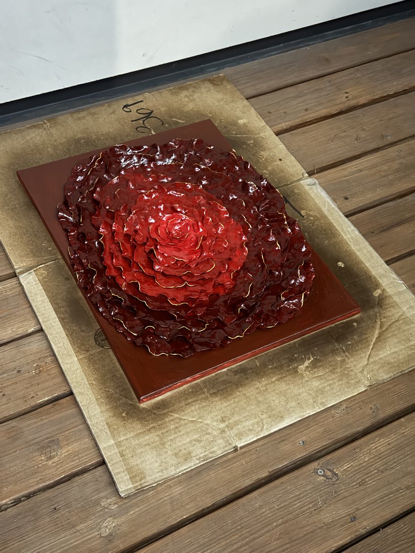 A deep red carved slab on a wooden stand