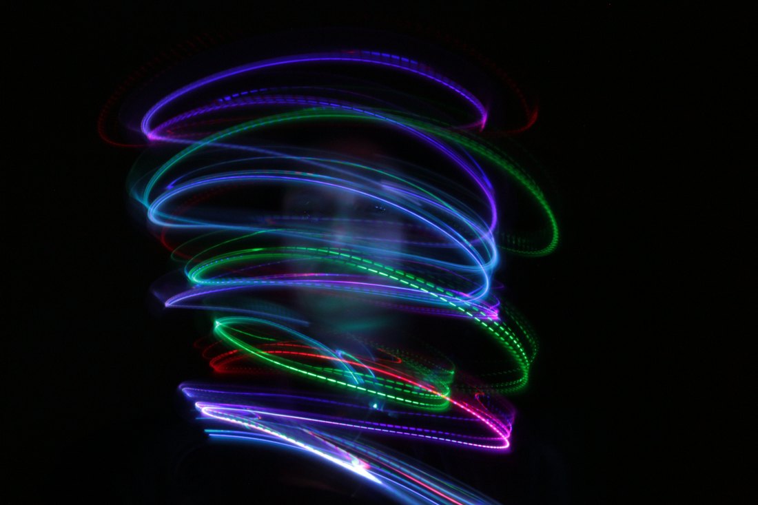 Wide overlapping loops of green, blue and violet light