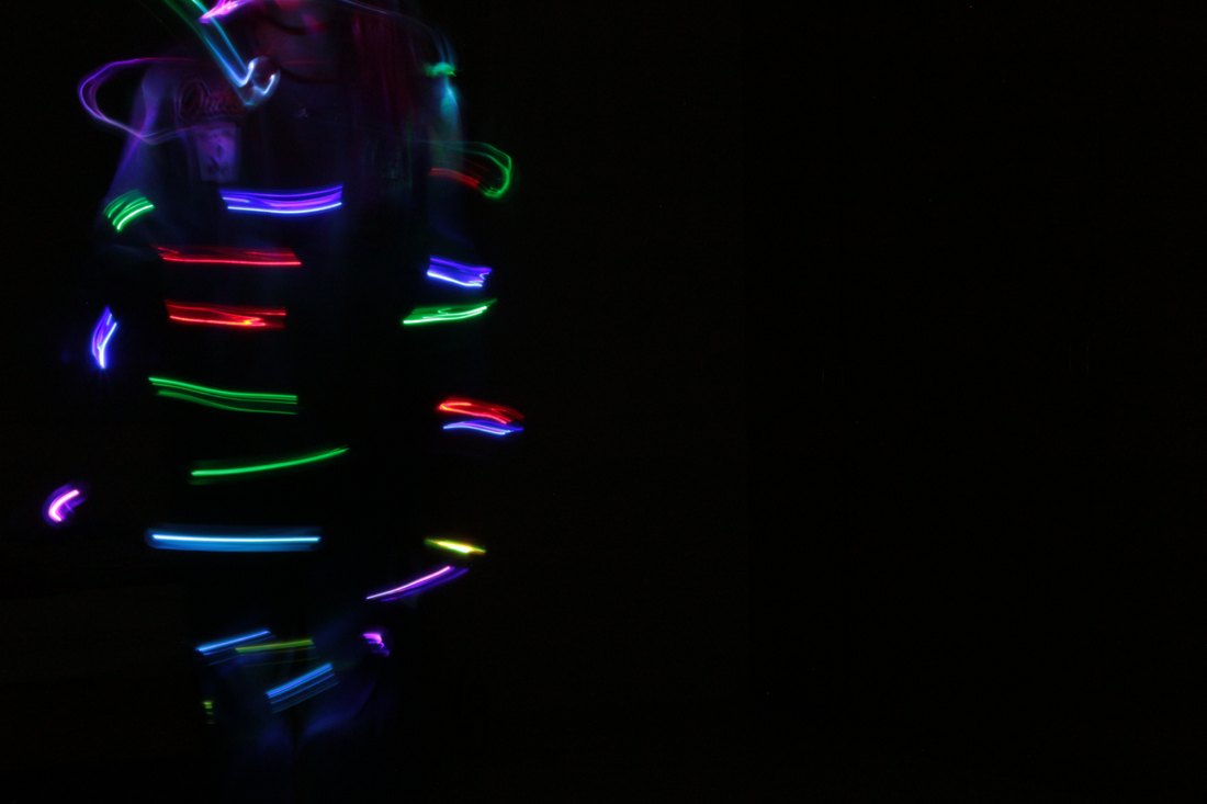 Short dashes of coloured light spiralling around a figure at the edge of the frame