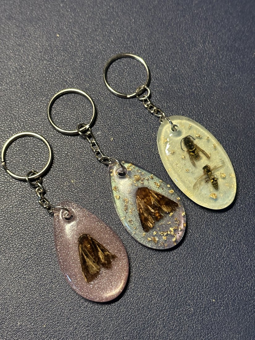 Three teardrop keychains, each with a bee inside