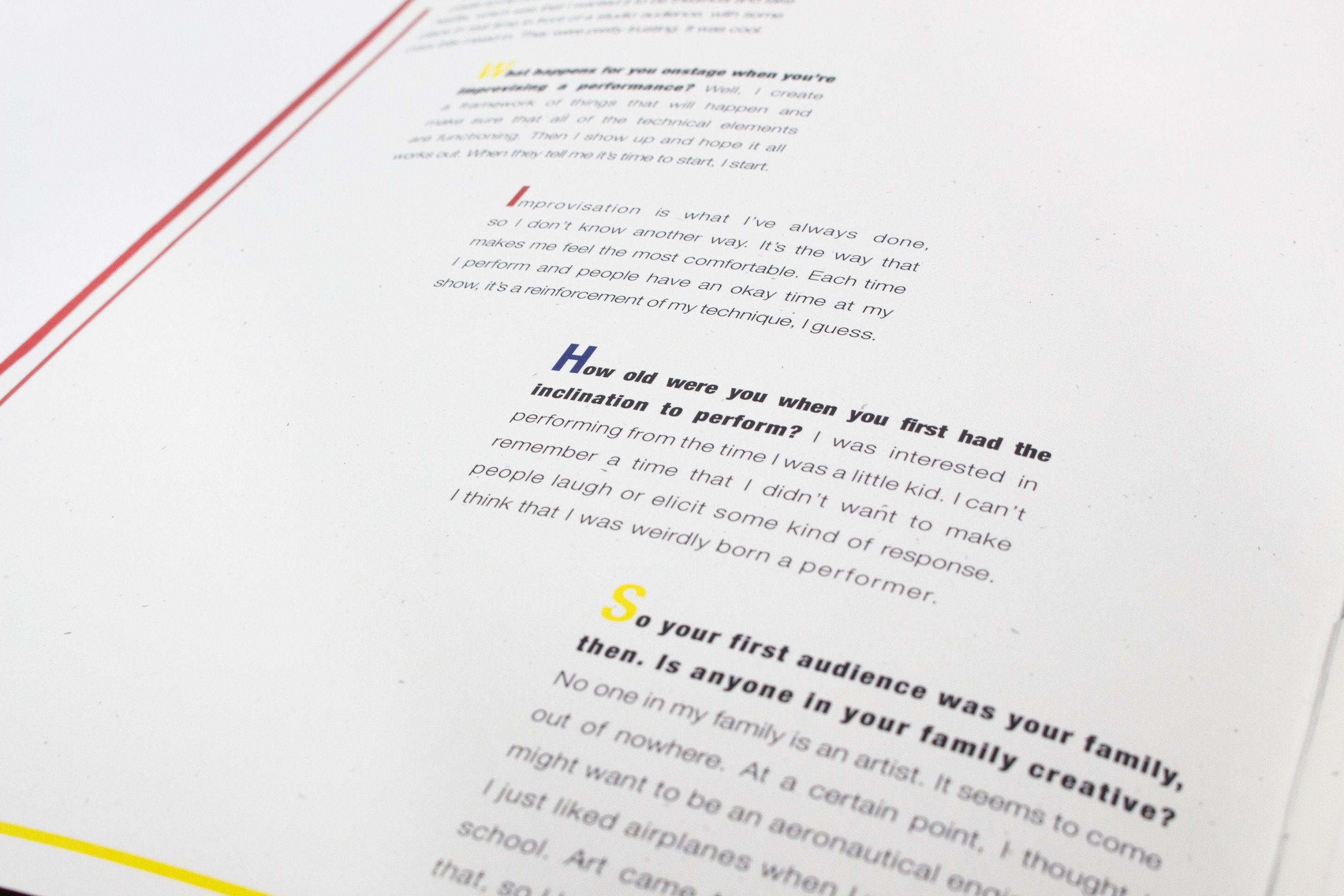 A raking view of a text spread, the questions set in blue and red italic against grey answer columns