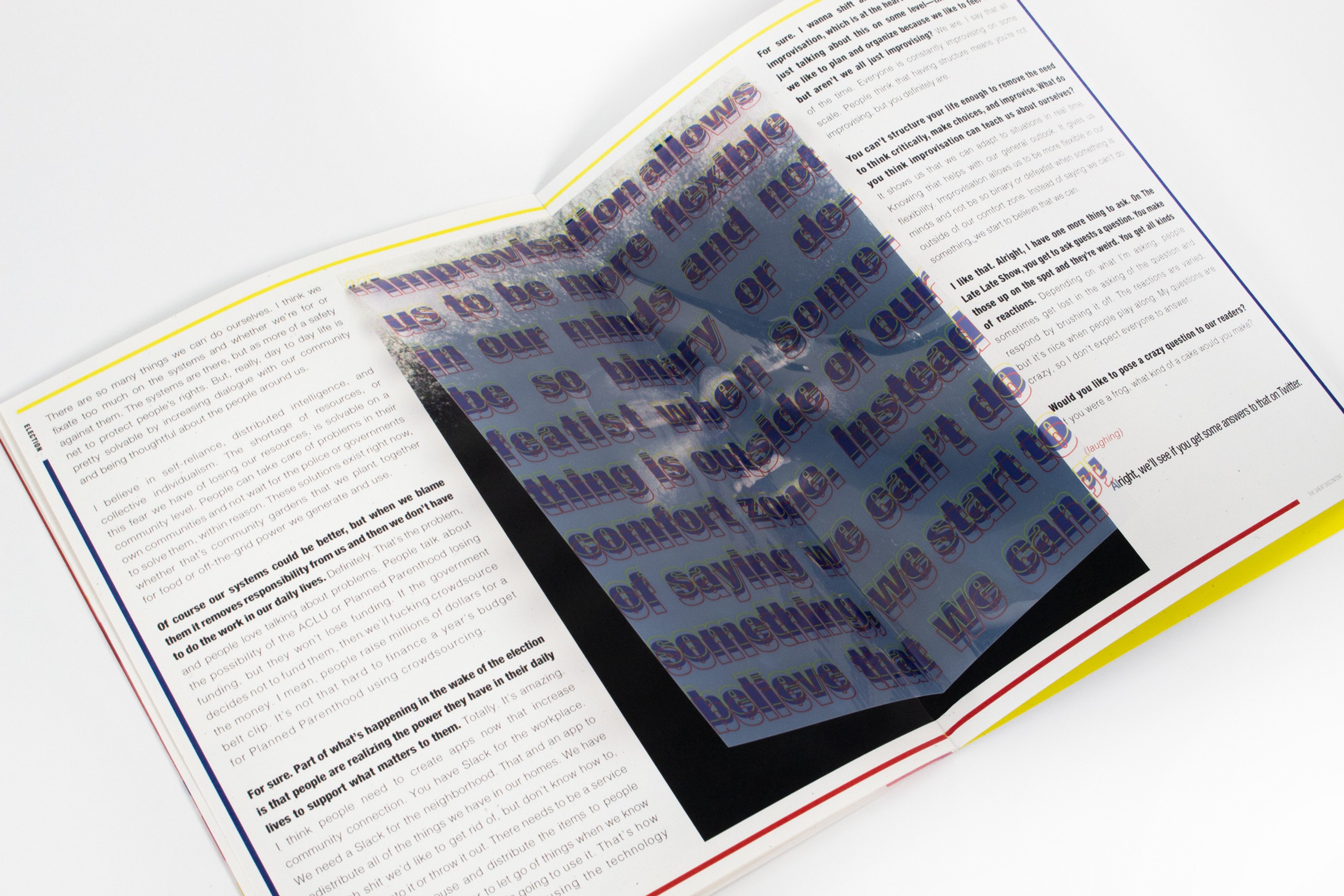 A spread photographed at an angle with a black page under the transparent sheet, so the overlaid type reads as white on black