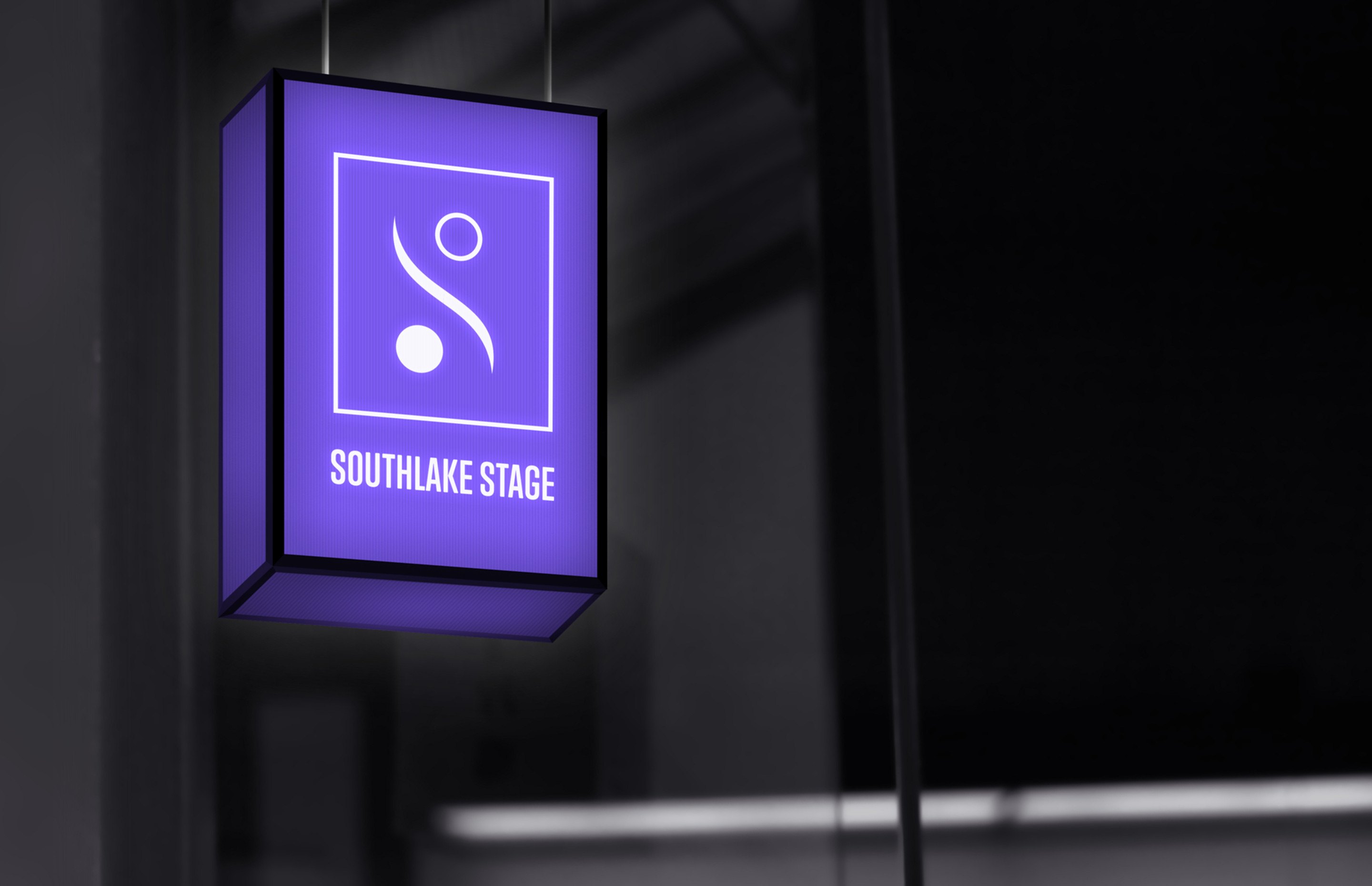 The signage: a hanging light-box in a dark interior, the two-sphere logo and SOUTHLAKE STAGE glowing violet against the black